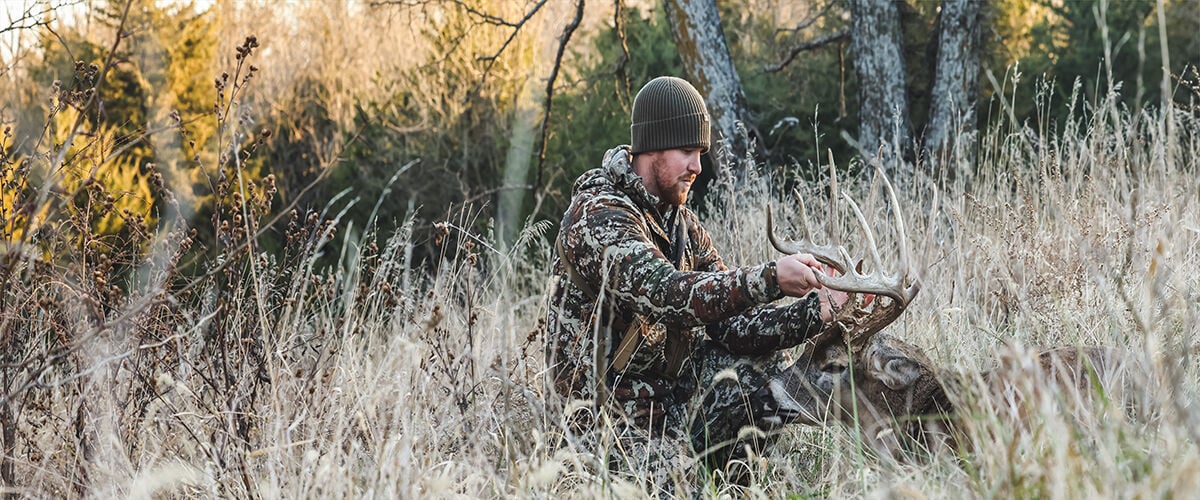 hunter sitting in field with deer